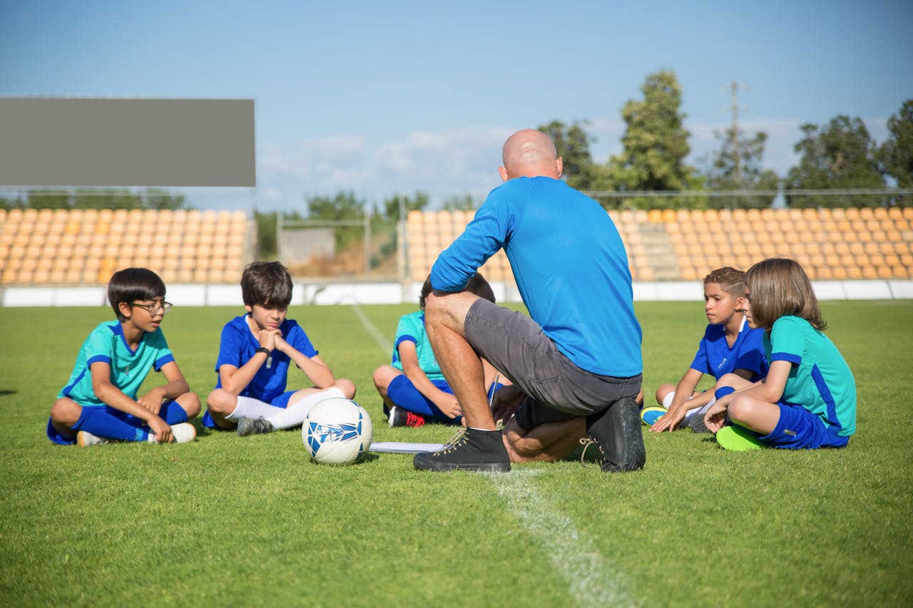 Group of kids receiving soccer coaching on a sunny day at a soccer field in Portugal.