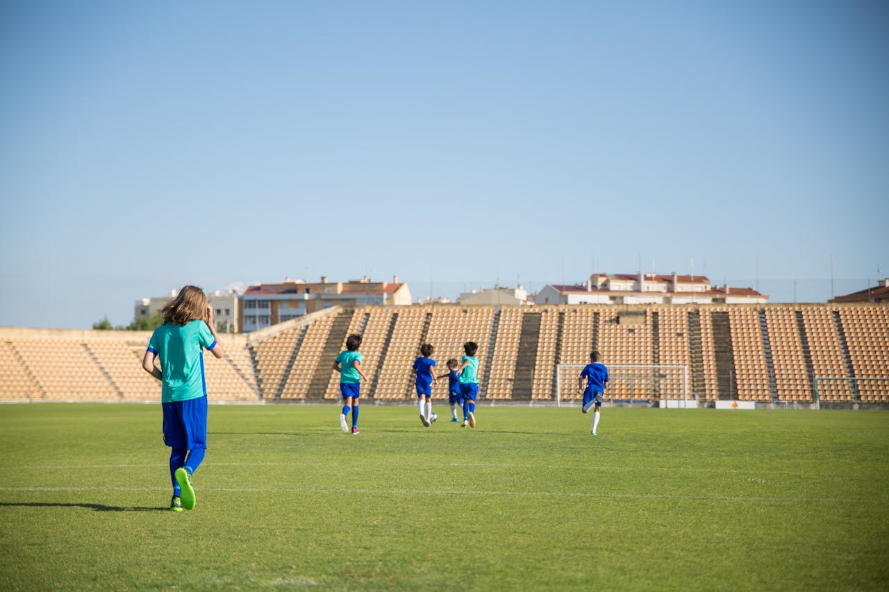Kids enjoying a soccer game on a sunny day in an outdoor stadium in Portugal.